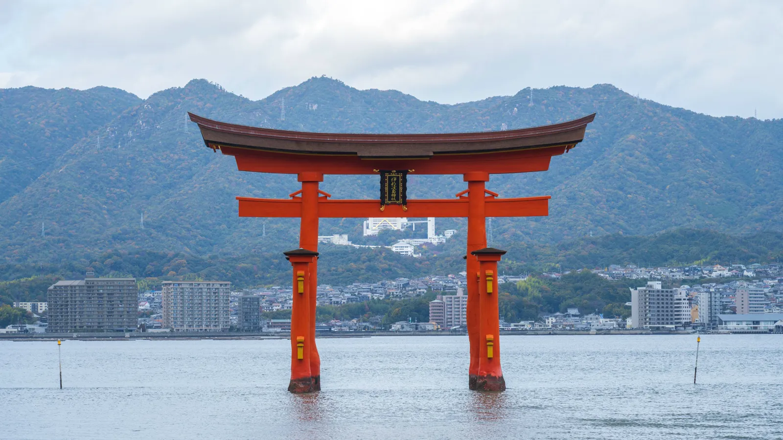 The red floating torii gate of Itsukushima Shrine standing in the sea off Miyajima, forested mountains behind